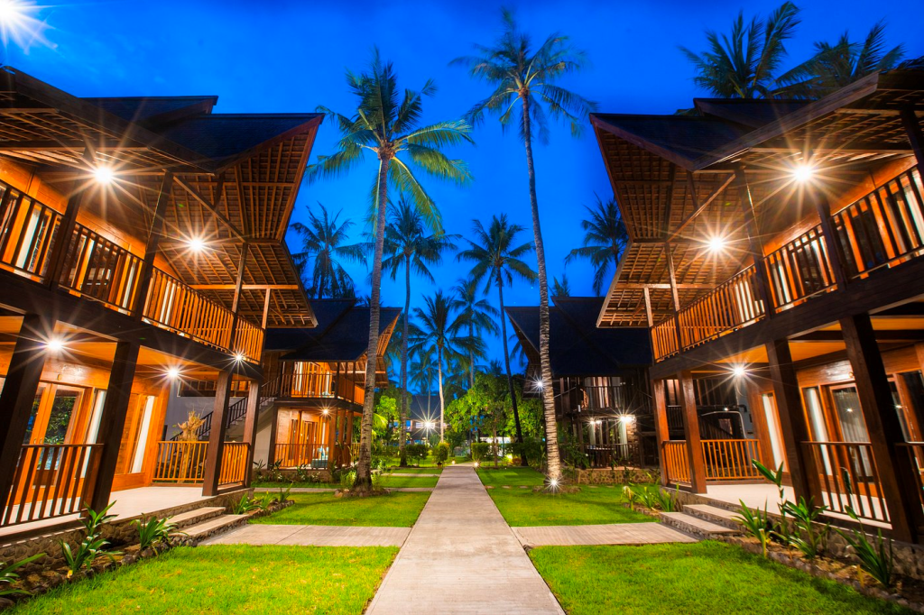 a row of traditional Balinese houses at The Kirana Tembok Resort Resort with palm trees in the background